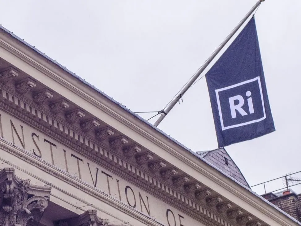 The Ri flag flying above the carved stone pediment of the Royal Institution